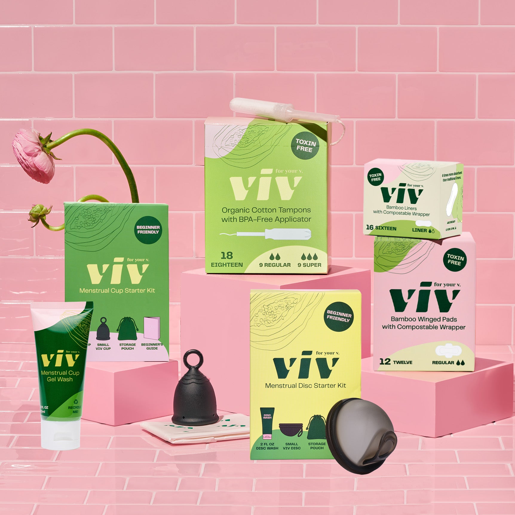 The Viv Menstrual Disc Starter Kit, Bamboo Liners, Bamboo Winged Pads, Viv Organic Cotton Tampons, and Viv Menstrual Cup Starter Kit sit on a pink tile background, giving you the chance to try all period products in the Viv lineup for a more sustainable and toxin-free period.