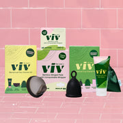 The Viv Menstrual Disc Starter Kit, Bamboo Liners, Bamboo Winged Pads, and Viv Menstrual Cup Starter Kit sit on a pink tile background, giving you the chance to try all period products in the Viv lineup for a more sustainable and toxin-free period.