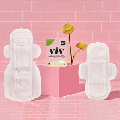 Viv Bamboo Winged Pads: Toxin-Free, Eco-Friendly Day Pads and Double-Winged Safe, Sustainable Night Pads sit on a pink tile backdrop next to a box of Viv Pads