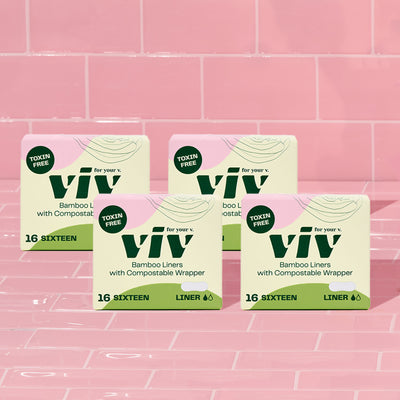 Four boxes of sustainable viv bamboo liners sitting in a room of pink tiles.